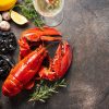 Fresh lobster with pasta, tomatoes, garlic, lemon and herbs on rustic background. Gourmet seafood meal ingredients