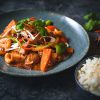 Delicious Asian stir-fry with vegetables and cashews served with white rice on a dark rustic table setting