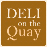 Sign with Deli on the Quay text in white on a brown background, promoting a delicatessen style eatery on the quay