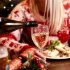 Pouring white wine into a glass at a festive dinner table with holiday decorations and delicious food