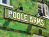 Poole Arms sign on a vibrant green tiled building exterior with vintage-style lamps above the entrance in Poole, UK