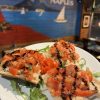 Italian bruschetta with tomatoes and balsamic glaze served on a white plate, restaurant wall art in background