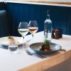 Elegant restaurant table setting with gourmet dishes, white and rosé wine glasses, and water bottle on a white tablecloth