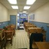 Cosy, empty café interior with wooden tables and blue accents, awaiting customers in a quaint neighbourhood setting