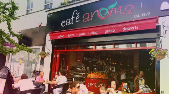 Café Aroma with outdoor seating, offering coffee, juices, pasta and desserts on a sunny day