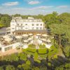 Aerial view of a luxury hotel with outdoor terraces, surrounded by lush greenery and blue skies