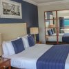 Elegant hotel room with double bed, navy accents and mirrored wardrobe, creating a spacious and serene atmosphere