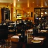 Elegant restaurant interior with neatly set tables, dim lighting, and wine displays, creating a cosy dining atmosphere