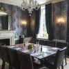 Elegant dining room with chandelier, ornate mirror, large table set for a meeting, dark wallpaper and curtains