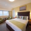 Cosy hotel room with sea view, featuring a double bed, stylish chairs, and soothing yellow decor for a relaxing stay