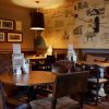 Cosy pub interior with vintage map wall decor, wooden tables, and warm lighting creating an inviting atmosphere
