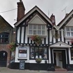 Historic King Charles pub with Tudor-style architecture, hanging flower baskets, located on cobblestone street