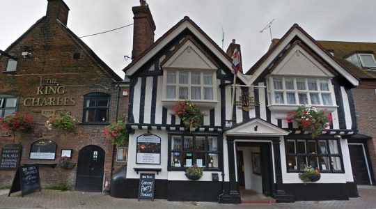 Historic King Charles pub with Tudor-style architecture, hanging flower baskets, located on cobblestone street