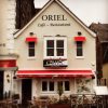 Oriel Café and Restaurant exterior with red awnings and outdoor seating, inviting atmosphere on the quay