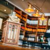 Rustic wooden lantern on a bar counter with wine bottles and warm lighting in the background of a cosy pub interior