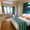 Modern hotel room with cosy double bed, teal accents, and large window for natural light