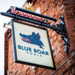 Blue Boar Poole pub sign featuring a blue boar head against a brick wall exterior in a traditional setting