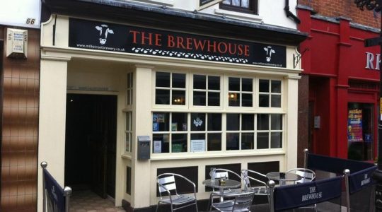 Facade of The Brewhouse pub featuring outdoor seating and large front windows on a street in England