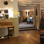 Cosy pub interior with festive Christmas tree, comfy seating, wooden floors and warm lighting for a welcoming atmosphere