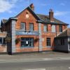 The New Inn Poole, a traditional brick pub with hanging baskets and blue accents under a clear sky