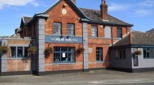 The New Inn Poole, a traditional brick pub with hanging baskets and blue accents under a clear sky