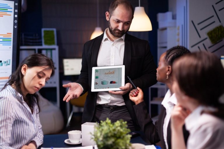 A man presents to an audience, engaging them with visual aids and discussion during a professional meeting