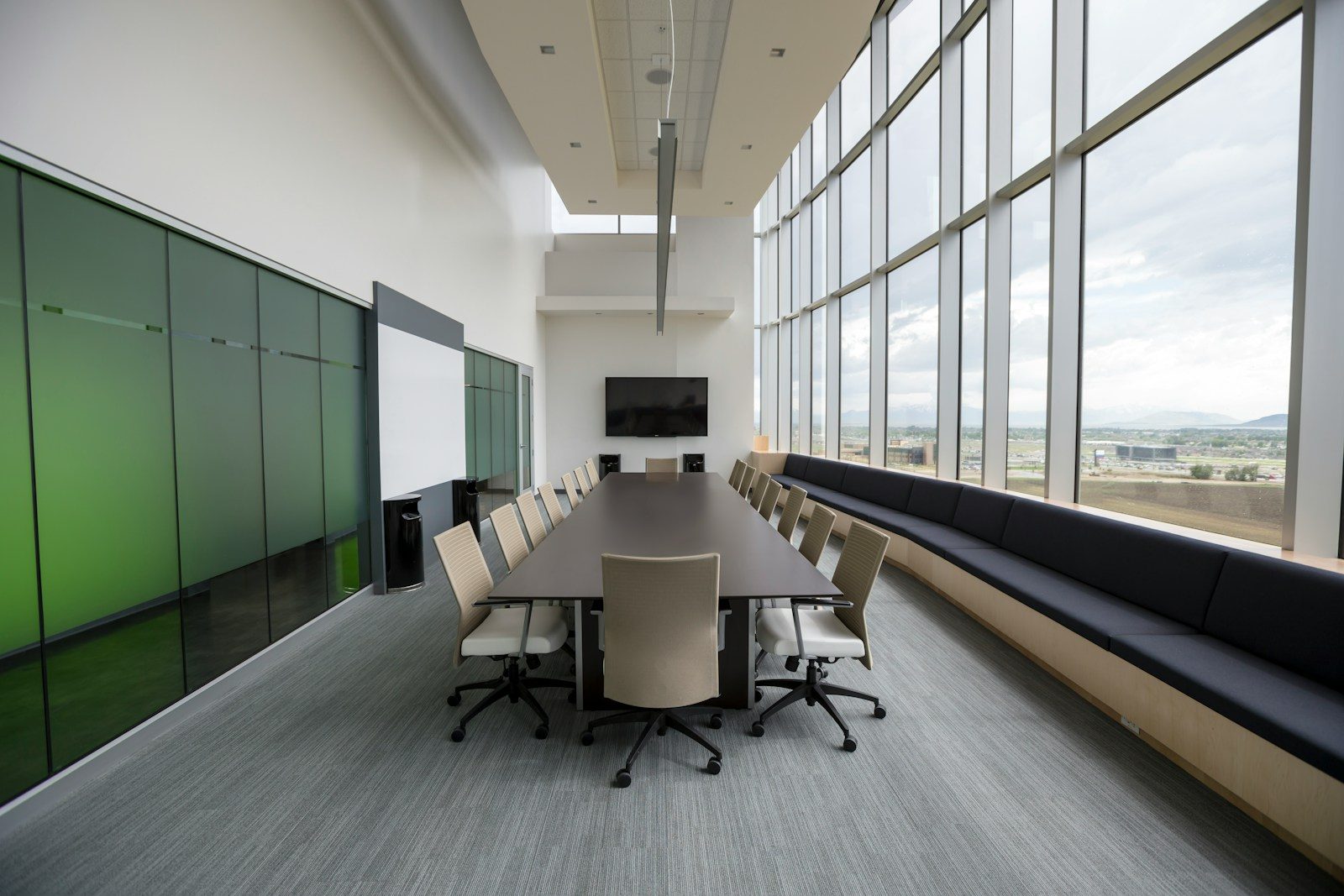 Modern conference room with large windows, long table, ergonomic chairs, and a screen for presentations