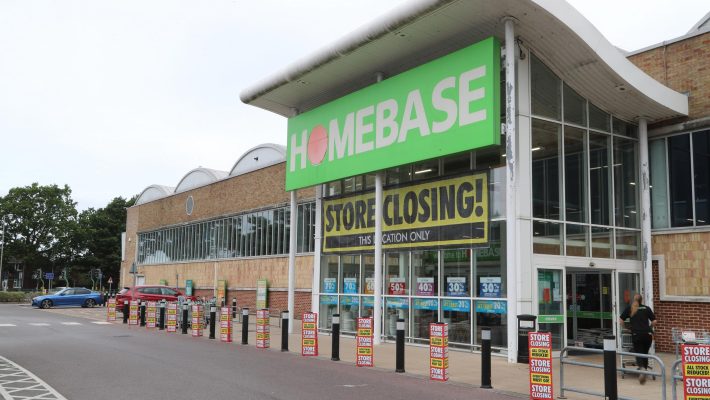 Homebase store with closing sale signs and discounts, large green sign above entrance, customer entering store