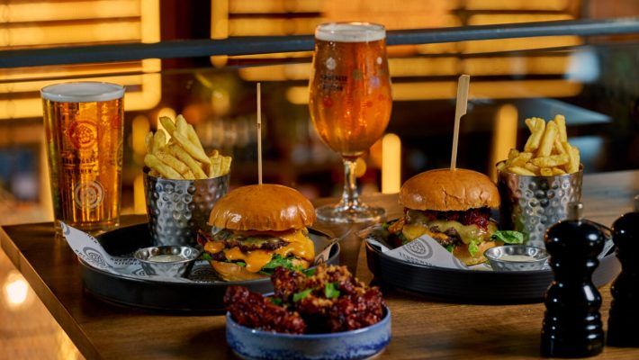 Burgers with chips and beer on a wooden table in a cosy pub setting, perfect for a casual dining experience