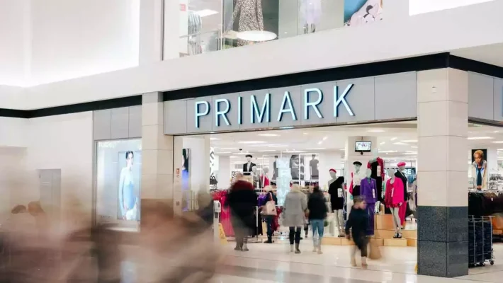 Primark store entrance bustling with shoppers at a mall displaying mannequins and fashion posters