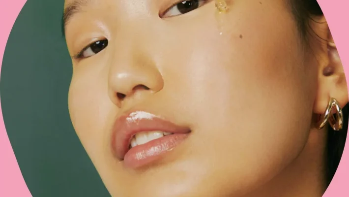 Woman applying facial serum with dropper for glowing skin care routine