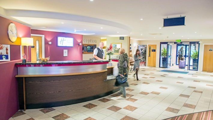 Bright hotel lobby with a welcoming reception desk, people checking in, and modern interior design