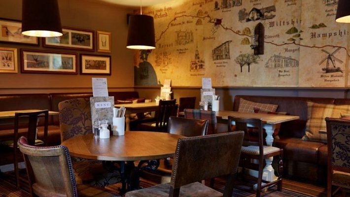 Cosy pub interior with vintage map wall decor, wooden tables, and warm lighting creating an inviting atmosphere