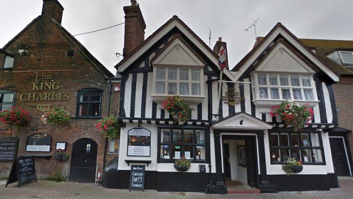 Historic King Charles pub with Tudor-style architecture, hanging flower baskets, located on cobblestone street