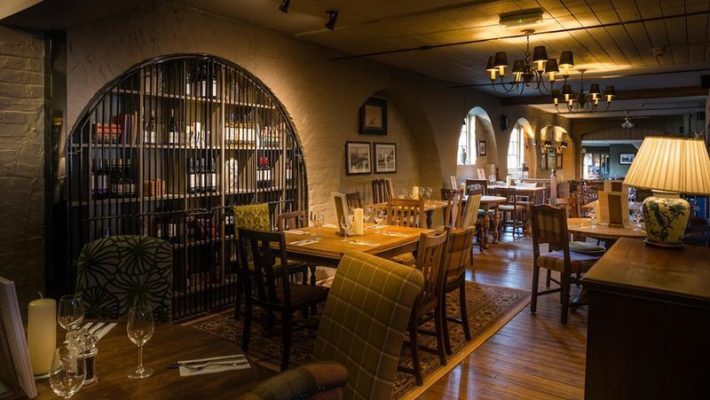 Cosy restaurant interior with wooden flooring, elegant lighting, and an inviting atmosphere for dining and socialising