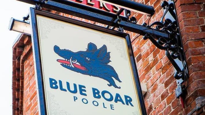 Blue Boar Poole pub sign featuring a blue boar head against a brick wall exterior in a traditional setting