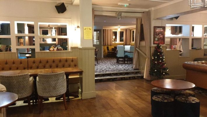 Cosy pub interior with festive Christmas tree, comfy seating, wooden floors and warm lighting for a welcoming atmosphere